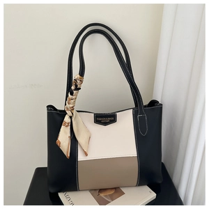 Detail van driekleurige leren tote bag met een decoratieve zijden sjaal aan het handvat