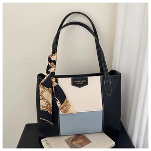 Detail van de kleurgeblokte shopper met zijden sjaal en luxe lederen textuur