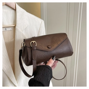 Detail of dark brown leather crossbody bag with envelope flap and sleek metal buckle