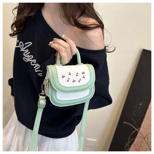 Detail of mint green cherry print mini bag with gold hardware and top handle