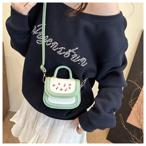 Detail of mint green cherry print crossbody bag with top handle and slim shoulder strap