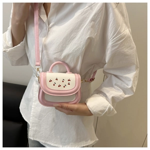 Pink and white mini crossbody bag with cherry prints shown on model for size and fit
