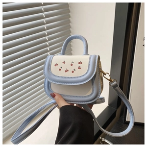 Detail of blue and white PU leather handbag featuring cute cherry print and gold hardware