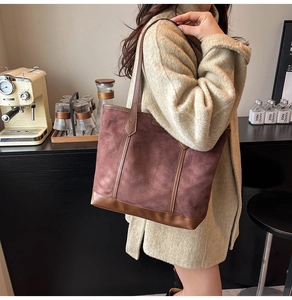 Detail of suede tote bag with contrast leather trim in a cozy cafe setting