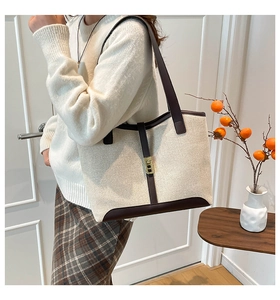 Detail of canvas tote bag featuring brown leather trim and golden metal buckle closure