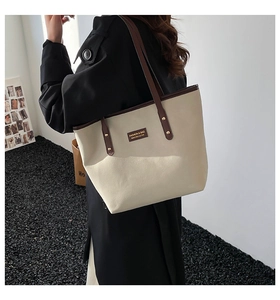 Canvas tote bag in beige and dark brown leather trim shown on model for size perspective