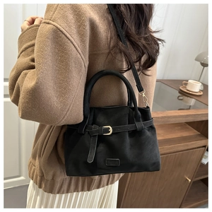 Detail of black suede tote bag with gold buckle and Fashion metal plate shown on model