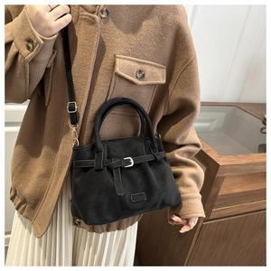 Detail of matte black suede-textured mini tote bag with adjustable shoulder strap