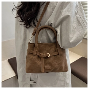 Detail of vintage brown suede tote bag showing texture and metal buckle on adjustable strap