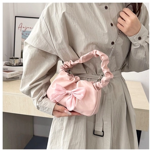 Détail du sac à main rose avec grand nœud en velours et bandoulière en chaîne chic