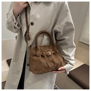 Brown faux suede tote bag with decorative buckle and dual handles shown on a model