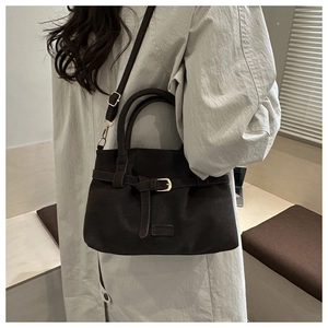 Detail of dark brown suede handbag with metal buckle strap and adjustable shoulder strap