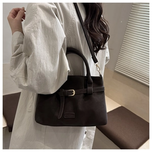 Detail of dark brown faux leather tote bag with buckle and fashion label shown on model