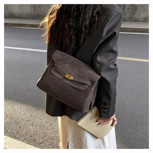 Detail of dark matte leather messenger bag with iconic gold hardware in street style