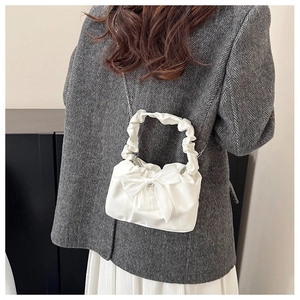 Detailed view of the white bow-knot pleated handbag with a slim metal chain strap