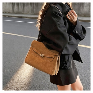 Detail view of brown matte suede tote bag with golden lock hardware in natural light