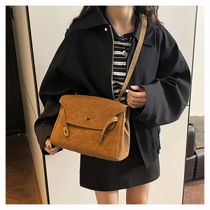 Detail of a brown vintage Kelly style bag showing the lock mechanism and matte texture