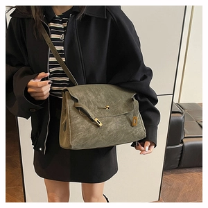Detail view of olive green crossbody bag with gold-tone hardware and buckle texture
