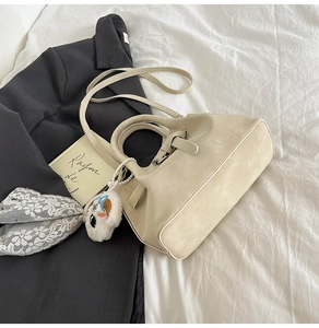 Sac à main en cuir blanc crème sur des draps blancs avec un joli porte-clés chien