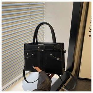 Detail of black retro handbag featuring belt buckle design and metallic rivet accents