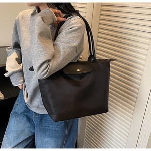 Detail showing high-quality black nylon material and premium leather handle on tote bag