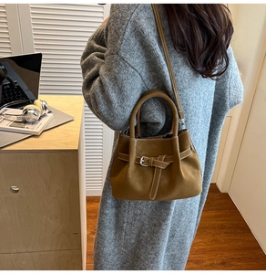 Gros plan d'un sac à main en cuir marron avec surpiqûres blanches et bandoulière amovible