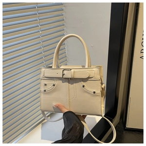 Detail of creamy white leather handbag featuring silver buckle and litchi grain texture