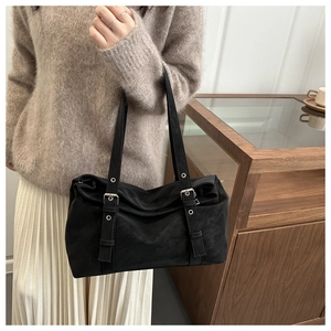 Détail d'un sac cabas en daim noir avec sangles décoratives et boucles argentées style rétro