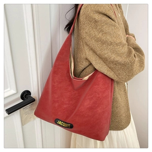 Detail of red oversized leather tote bag showing vintage texture and Jacqueue brand tag