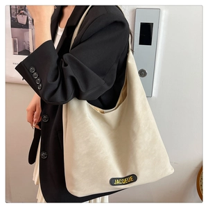 Detail of minimalist cream tote bag showing soft leather texture and branded leather logo