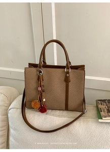 Detail of retro tote bag with brown leather trim and fluffy charm on a sofa