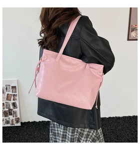 Detailed view of pink embossed tote bag with large capacity shown on model in stylish outfit