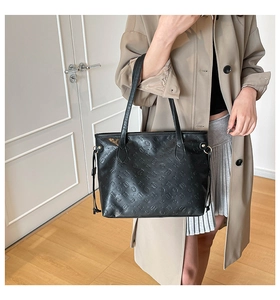 Detail of black leather tote bag featuring an all-over embossed cat pattern finish
