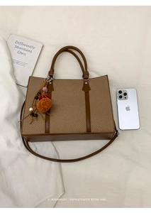 Detail of vintage brown woven tote bag with plush pompom charm and adjustable strap