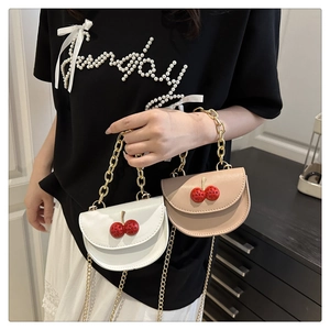 Détail de sacs bandoulière semi-circulaires avec cerises 3D et chaînes dorées