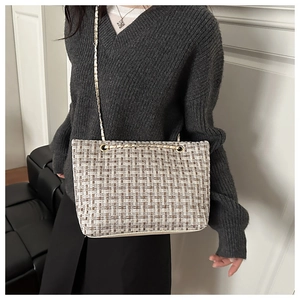 Detail of woven textured shoulder bag with chic pattern and gold chain strap