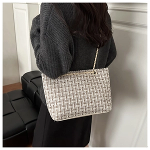 Detail of the checkered tweed tote bag with golden chain strap on model's shoulder