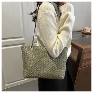 Detail view of woven tweed tote bag with light green plaid and golden chain strap