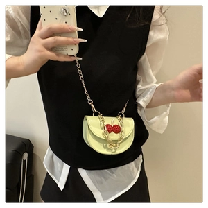 Vue détaillée du mini sac bandoulière en cuir vert avec breloque cerise et chaîne dorée