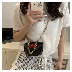 Selfie miroir montrant un mini sac de selle noir avec cerise et chaîne dorée