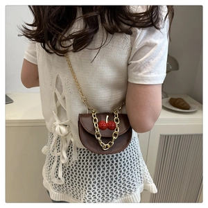 Detail of a brown leather crossbody bag featuring 3D cherry accents and gold chain strap