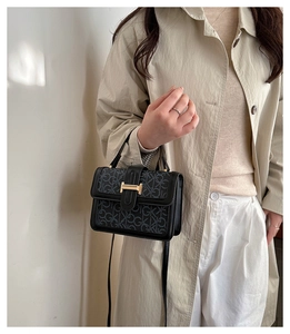 Detail of trendy crossbody bag with retro buckle and letter print on textured leather