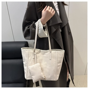 Détail du cabas beige minimaliste avec petite pochette zippée porté par un mannequin