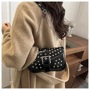Detail of black glossy leather bag with silver punk rivets and metal buckle on shoulder strap