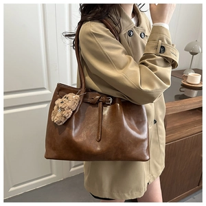 Détail d'un grand sac cabas en cuir marron foncé avec pendentif ours en peluche doux