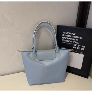 Detail of light blue nylon tote bag with long handles and golden snap closure button