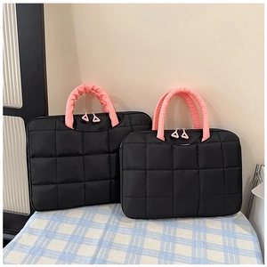 Detail of black quilted laptop bags with pink ruffled handles and triangle zipper pull