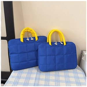 Detail of waterproof quilted blue laptop bags featuring contrasting yellow handles