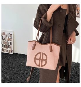 Detail of pink woven tote bag featuring dark brown leather straps and signature logo