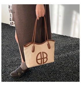 Detail of woven beige tote bag with brown leather trim and circular logo emblem